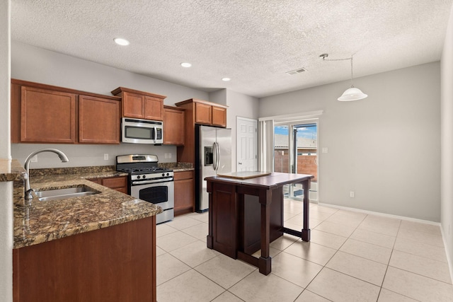 kitchen with light tile patterned floors, brown cabinetry, appliances with stainless steel finishes, and a sink