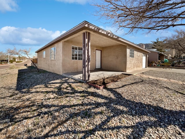 view of side of property featuring stucco siding, an attached garage, and a patio area