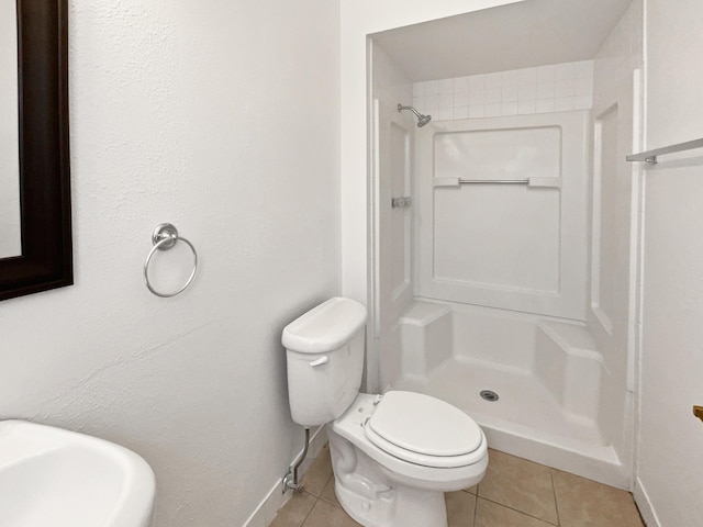 full bathroom with tile patterned floors, toilet, a stall shower, a sink, and baseboards