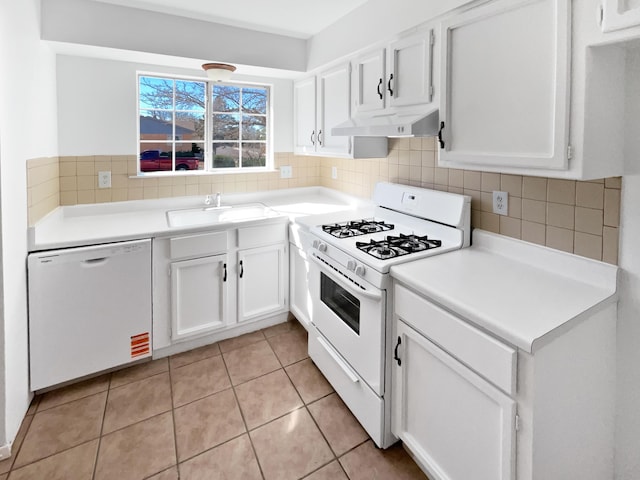 kitchen featuring under cabinet range hood, decorative backsplash, white appliances, white cabinetry, and a sink