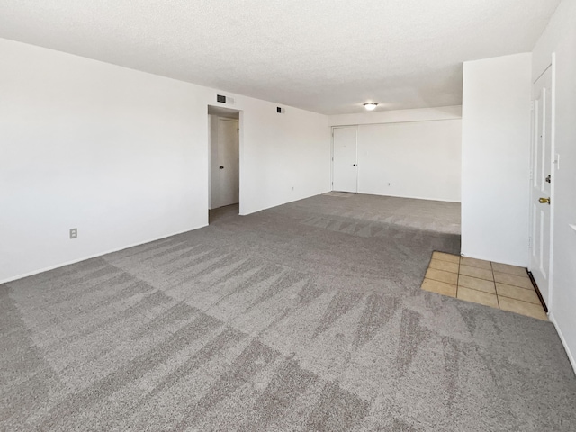 carpeted empty room featuring visible vents and a textured ceiling