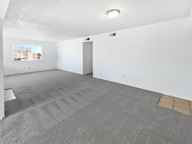 unfurnished room with visible vents, carpet, and a textured ceiling