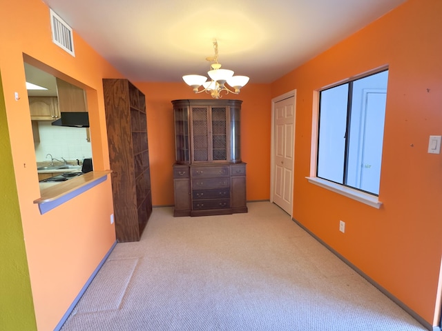 unfurnished dining area featuring visible vents, light colored carpet, and a chandelier