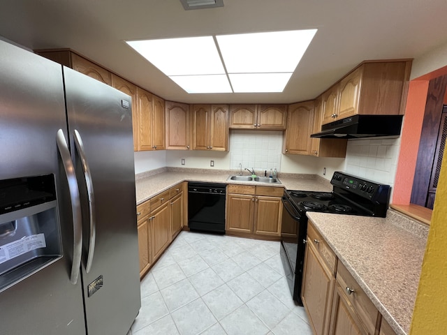 kitchen with black appliances, under cabinet range hood, a sink, light countertops, and decorative backsplash