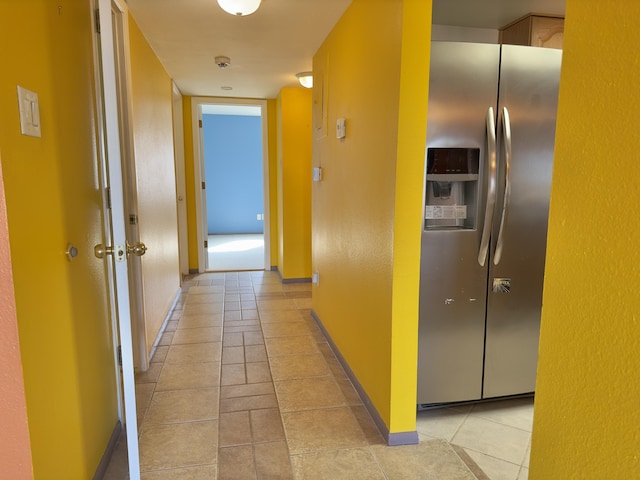 corridor featuring light tile patterned flooring and baseboards