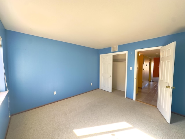 unfurnished bedroom with visible vents, carpet floors, and a closet