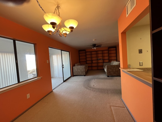 interior space with visible vents, light carpet, and ceiling fan with notable chandelier