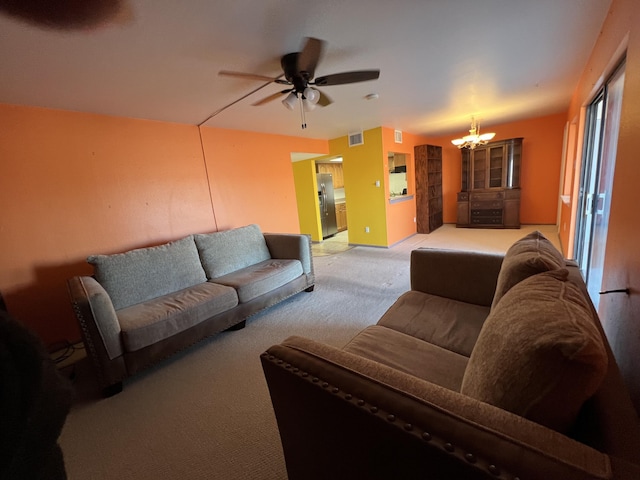 living area with visible vents, light carpet, and ceiling fan with notable chandelier