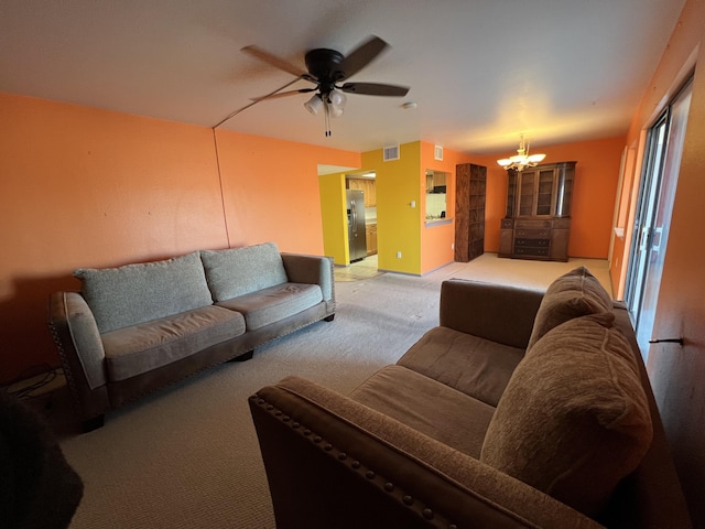 living area with visible vents, ceiling fan with notable chandelier, and light colored carpet