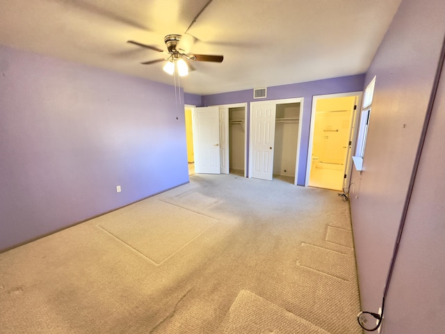 unfurnished bedroom with two closets, a ceiling fan, visible vents, and carpet floors