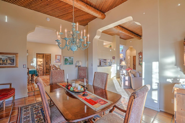 dining space featuring arched walkways, beam ceiling, and wooden ceiling