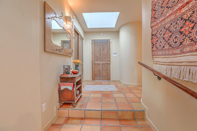 entryway featuring tile patterned flooring, a skylight, and baseboards