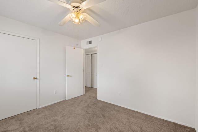 unfurnished bedroom with carpet flooring, a textured ceiling, visible vents, and a ceiling fan