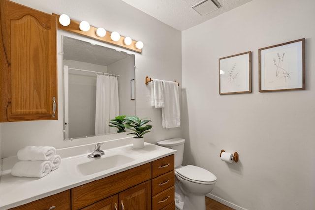 bathroom with visible vents, curtained shower, toilet, vanity, and a textured ceiling