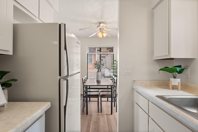 kitchen with white cabinets, light countertops, freestanding refrigerator, and a ceiling fan