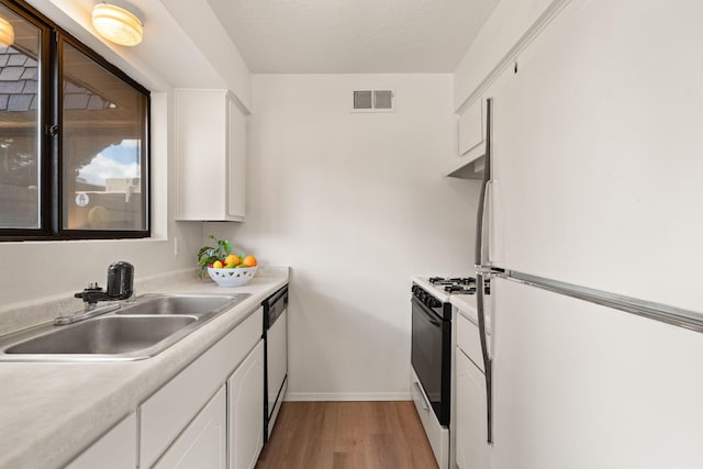 kitchen featuring a sink, gas range, freestanding refrigerator, white cabinetry, and stainless steel dishwasher