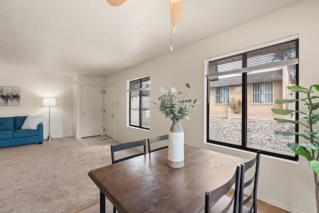 dining area featuring light carpet, a textured ceiling, and ceiling fan