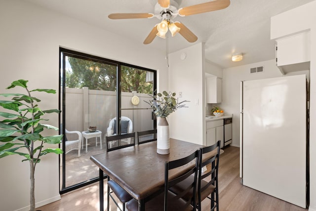 dining room with light wood-style flooring, a ceiling fan, and visible vents