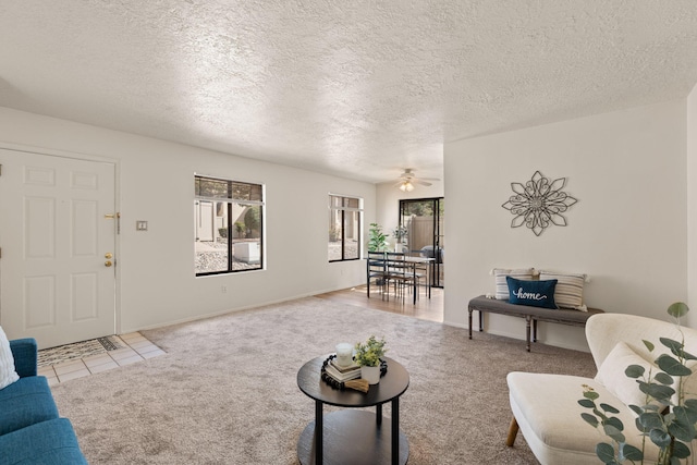 carpeted living area with baseboards, a textured ceiling, a ceiling fan, and tile patterned flooring