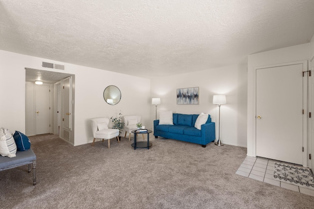 living room with tile patterned floors, visible vents, carpet flooring, and a textured ceiling