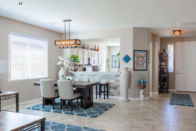 dining space featuring light tile patterned floors, baseboards, visible vents, and a textured ceiling