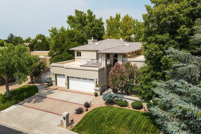 view of front of home with concrete driveway, stucco siding, a chimney, a garage, and a balcony