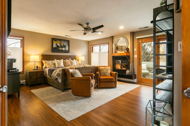 bedroom with a textured ceiling, visible vents, dark wood-type flooring, and access to outside