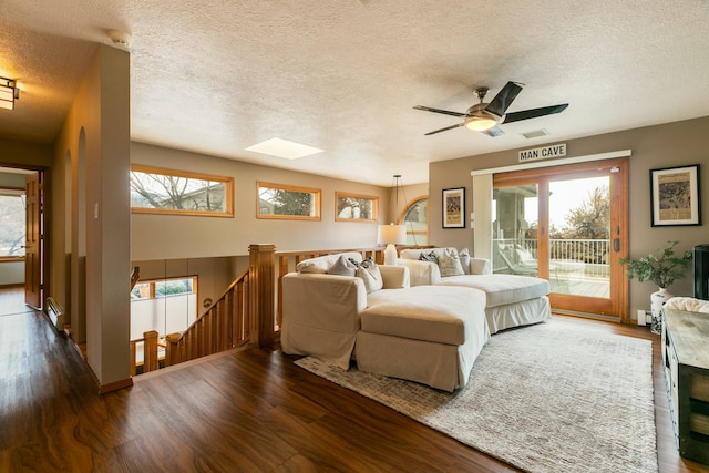 bedroom with access to exterior, visible vents, a skylight, wood finished floors, and a textured ceiling