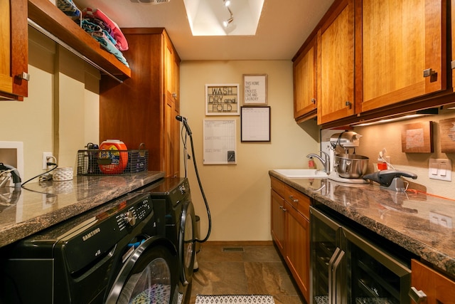 washroom featuring baseboards, cabinet space, a sink, wine cooler, and washing machine and dryer