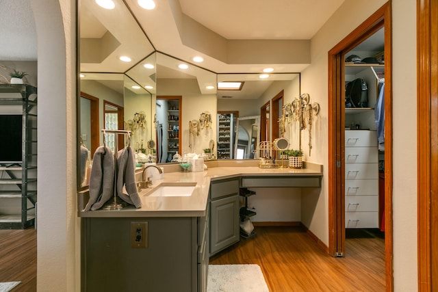 full bathroom featuring a spacious closet, baseboards, recessed lighting, wood finished floors, and vanity