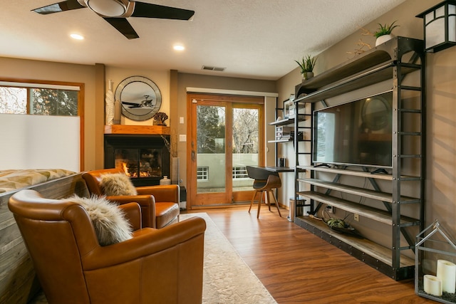 living room with visible vents, wood finished floors, recessed lighting, a large fireplace, and ceiling fan