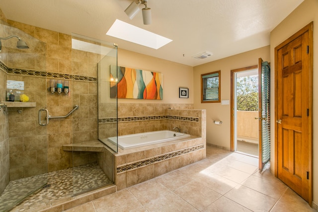 bathroom with a stall shower, a garden tub, a skylight, and tile patterned floors