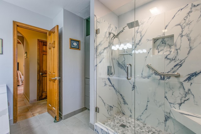 bathroom featuring a marble finish shower and tile patterned floors