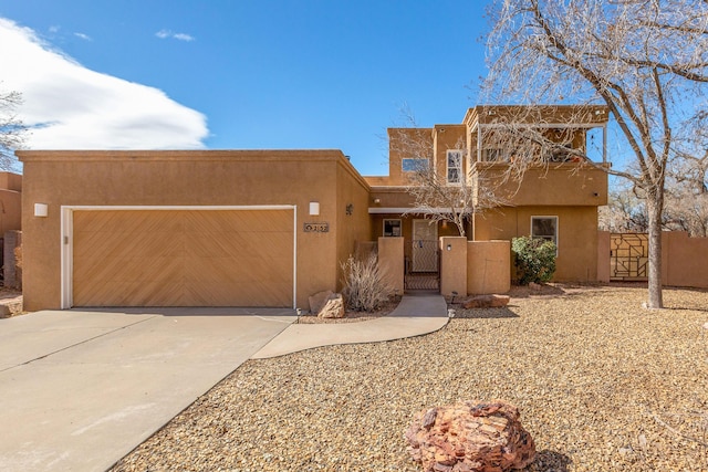 adobe home with stucco siding, a garage, and a gate