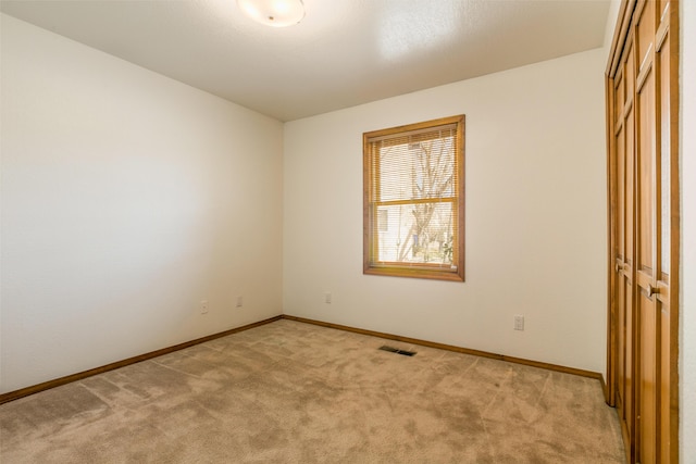 unfurnished bedroom with light carpet, visible vents, a closet, and baseboards