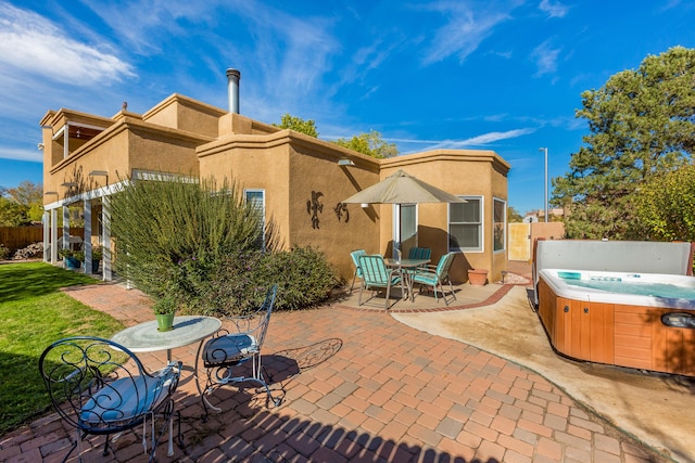 view of patio / terrace with a hot tub and fence