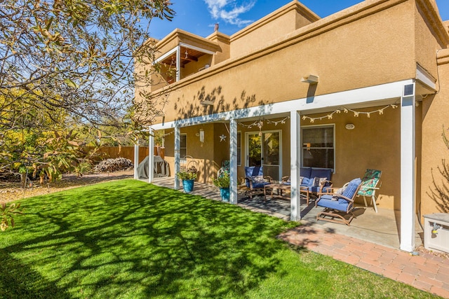 back of property with a patio area, an outdoor living space, stucco siding, and a lawn