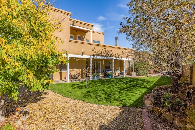 back of property with a patio area, a lawn, and stucco siding