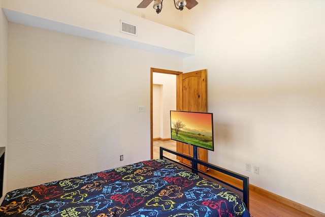 bedroom with baseboards, wood finished floors, visible vents, and ceiling fan