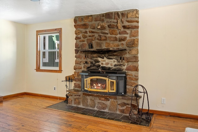 interior details with a stone fireplace, baseboards, and wood finished floors