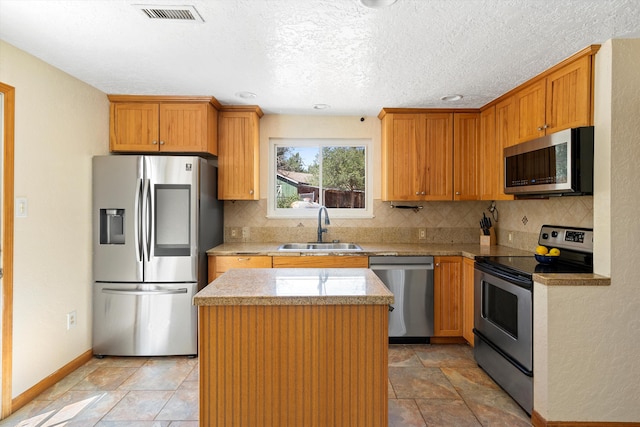 kitchen featuring visible vents, a sink, tasteful backsplash, a center island, and appliances with stainless steel finishes