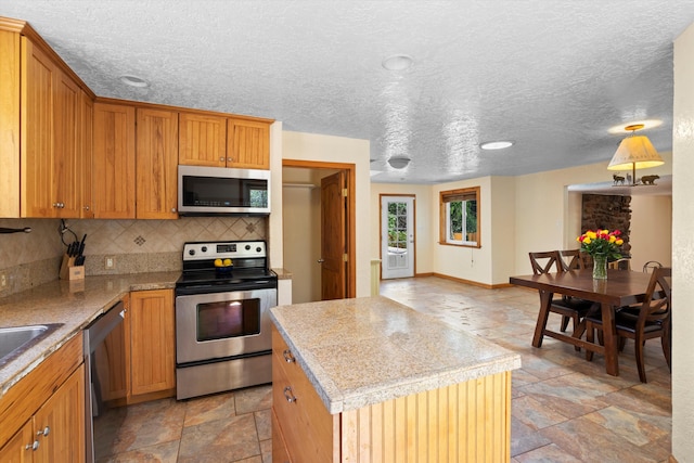 kitchen featuring tasteful backsplash, stone tile flooring, a center island, stainless steel appliances, and light countertops