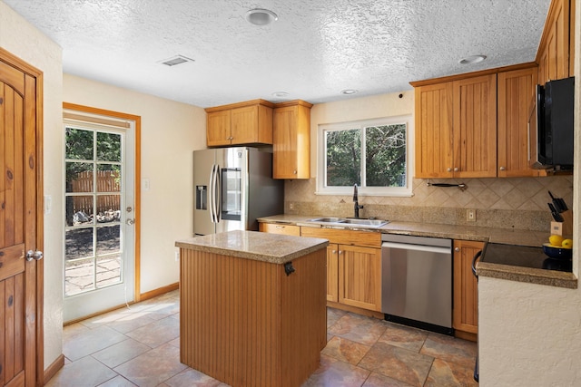 kitchen with a sink, a kitchen island, backsplash, and appliances with stainless steel finishes