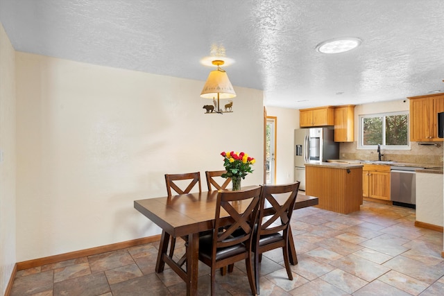 dining space with a textured ceiling, baseboards, and stone finish flooring