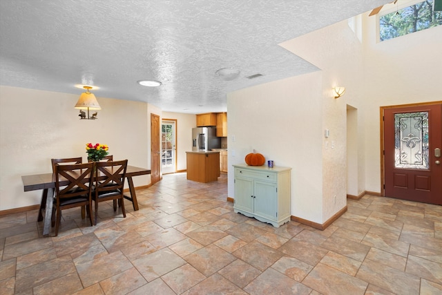 entrance foyer featuring visible vents, baseboards, a textured ceiling, and stone finish flooring