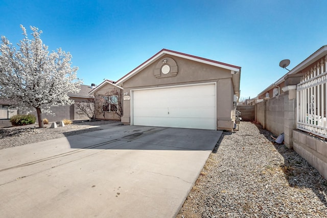 view of front of property with stucco siding, concrete driveway, an outdoor structure, and fence