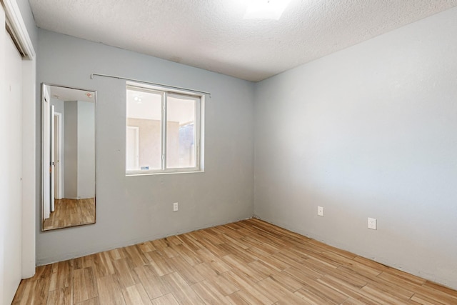 unfurnished room with light wood finished floors and a textured ceiling