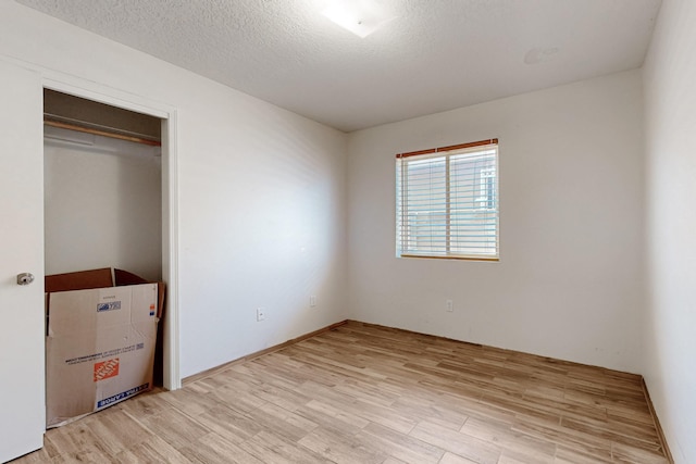 unfurnished bedroom with light wood finished floors and a textured ceiling