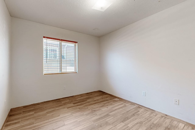 unfurnished room featuring light wood-style flooring and a textured ceiling