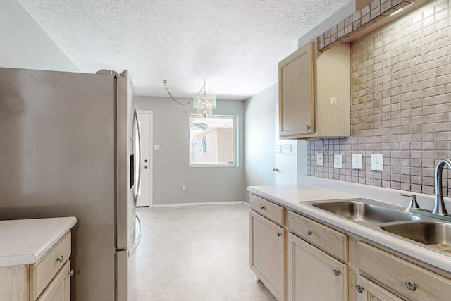 kitchen featuring backsplash, stainless steel fridge with ice dispenser, light countertops, a textured ceiling, and a sink